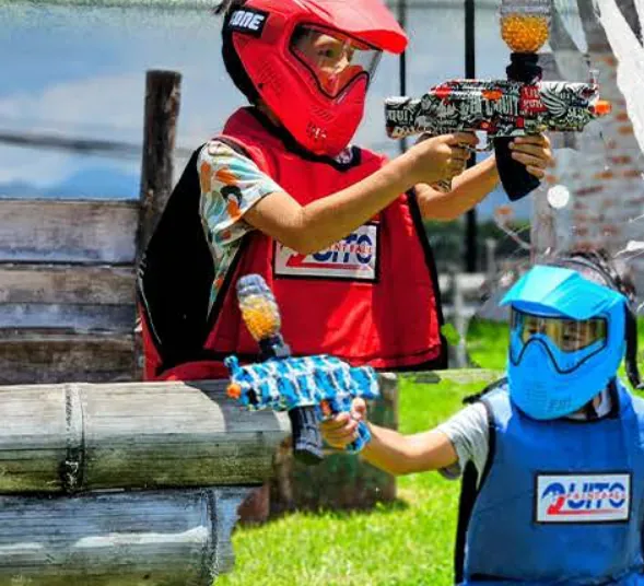 Dos niños con máscara y chaleco juegan con marcadoras de Gel Blaster