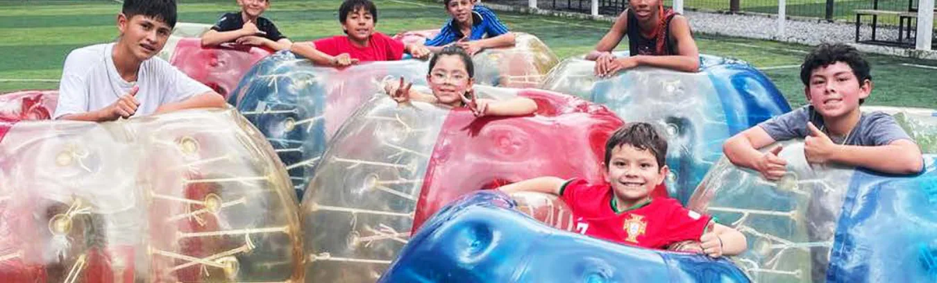 Niños sonrientes dentro de burbujas inflables sobre la cancha sintética