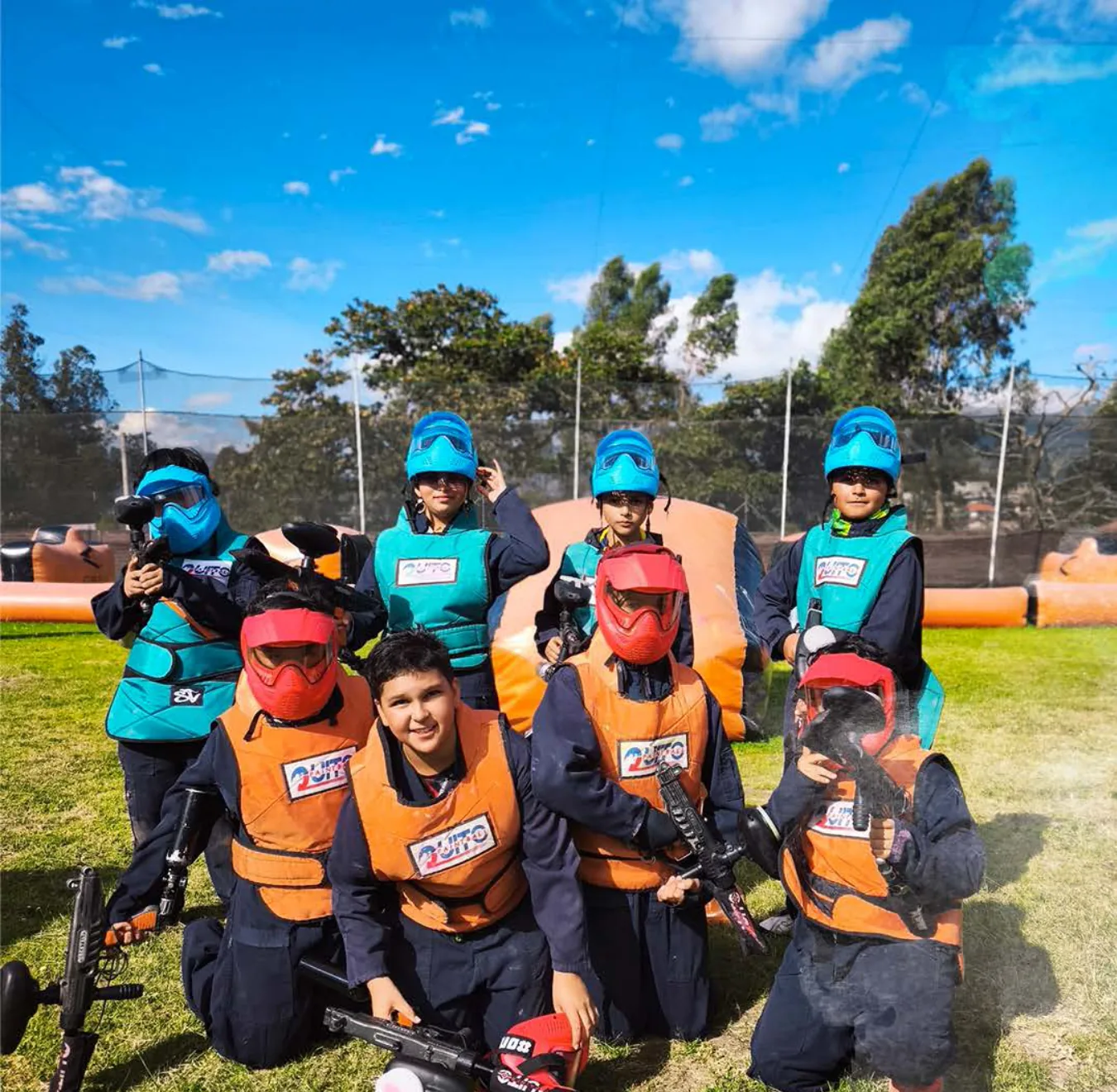 Grupo de niños con máscaras y chalecos de QuitoPaintball posa con sus marcadoras